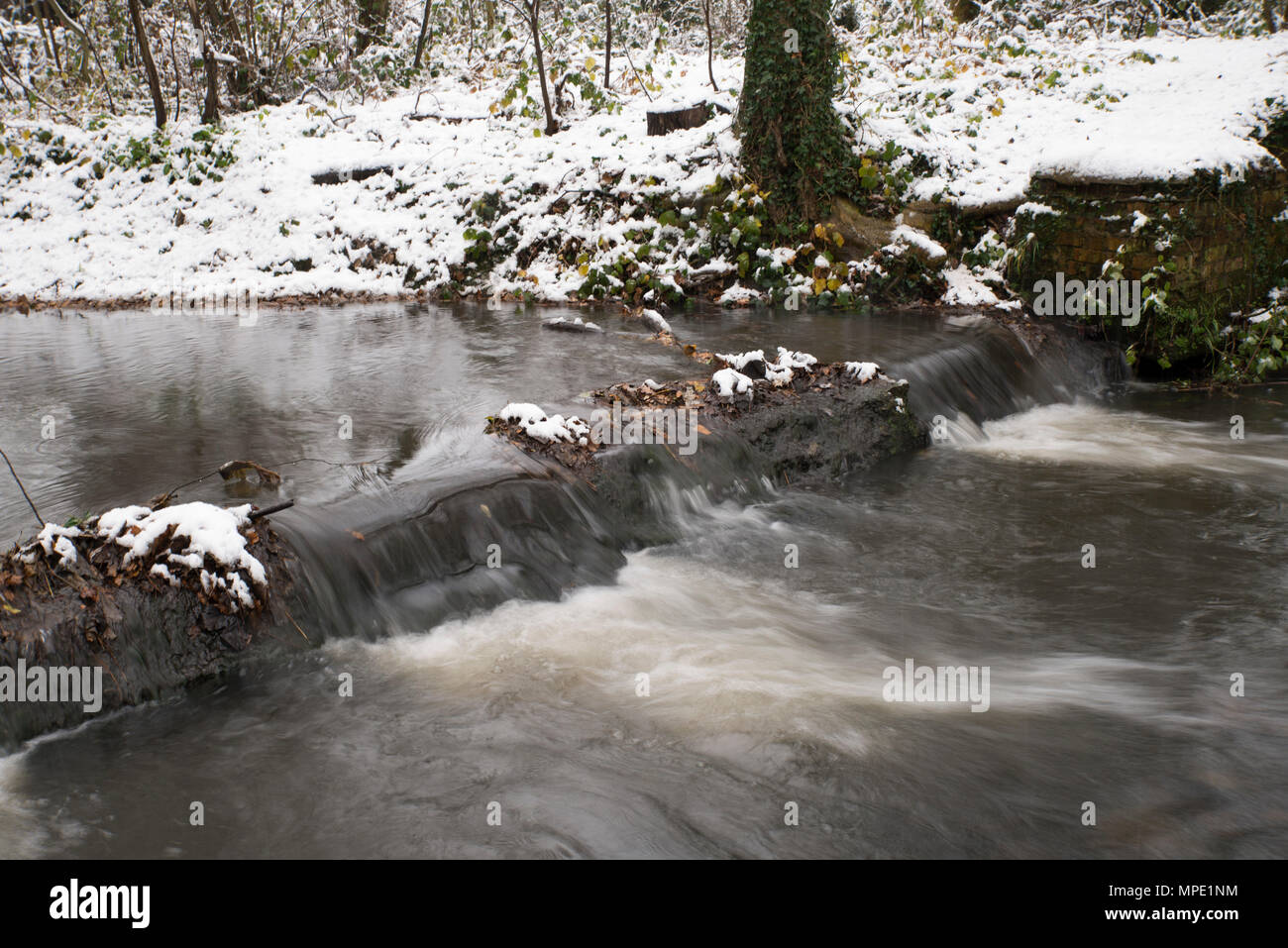 Weir au-dessus d'un petit ruisseau à Dolis Brook, Londres pendant l'hiver Banque D'Images