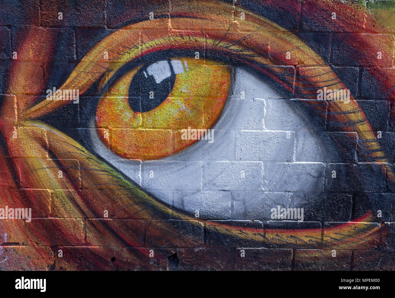 Peinture sur un mur de brique d'un grand œil jaune à la vers le haut. Banque D'Images