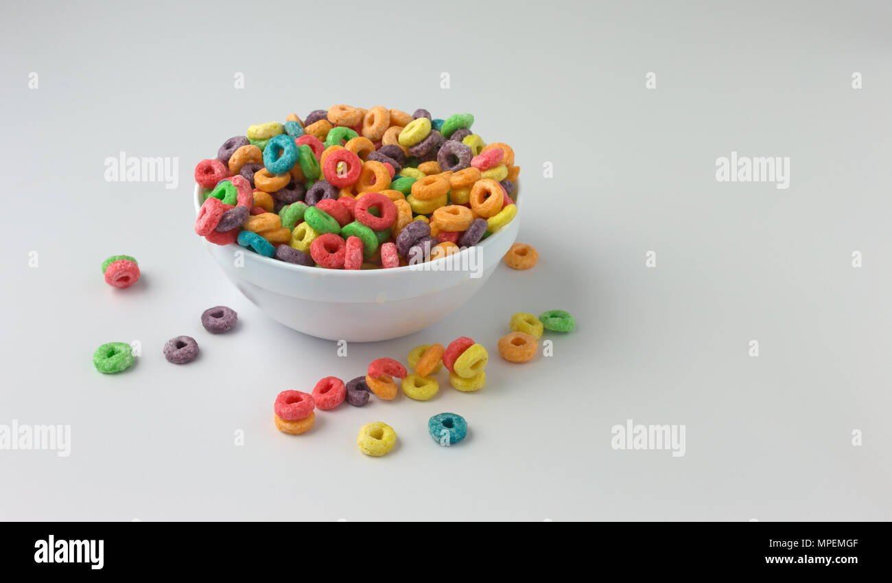 Un bol rempli de dragées aux génériques de céréales de petit déjeuner à saveur fruitée avec du lait et céréales renversé sur une table. Banque D'Images Un bol rempli de dragées aux génériques de céréales de petit déjeuner à saveur fruitée avec du lait et céréales renversé sur une table. Banque D'Images