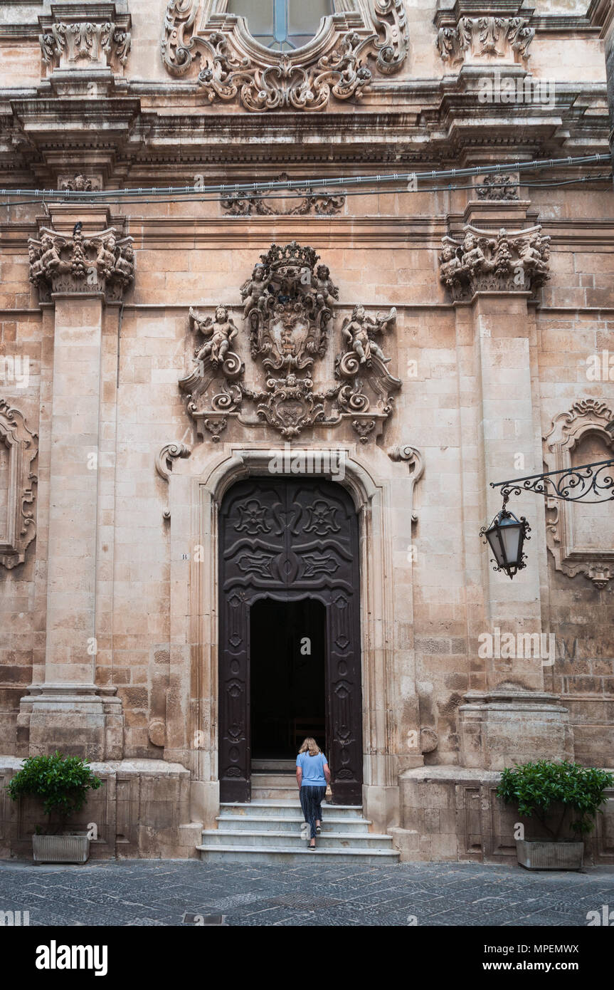 Une femme seule monte les marches de l'entrée de la Chiesa di San Domenico, Martina Franca, Pouilles, Italie. Banque D'Images