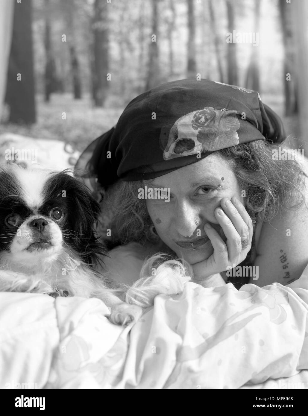 Femme au lit avec son chien Chin japonais. Banque D'Images