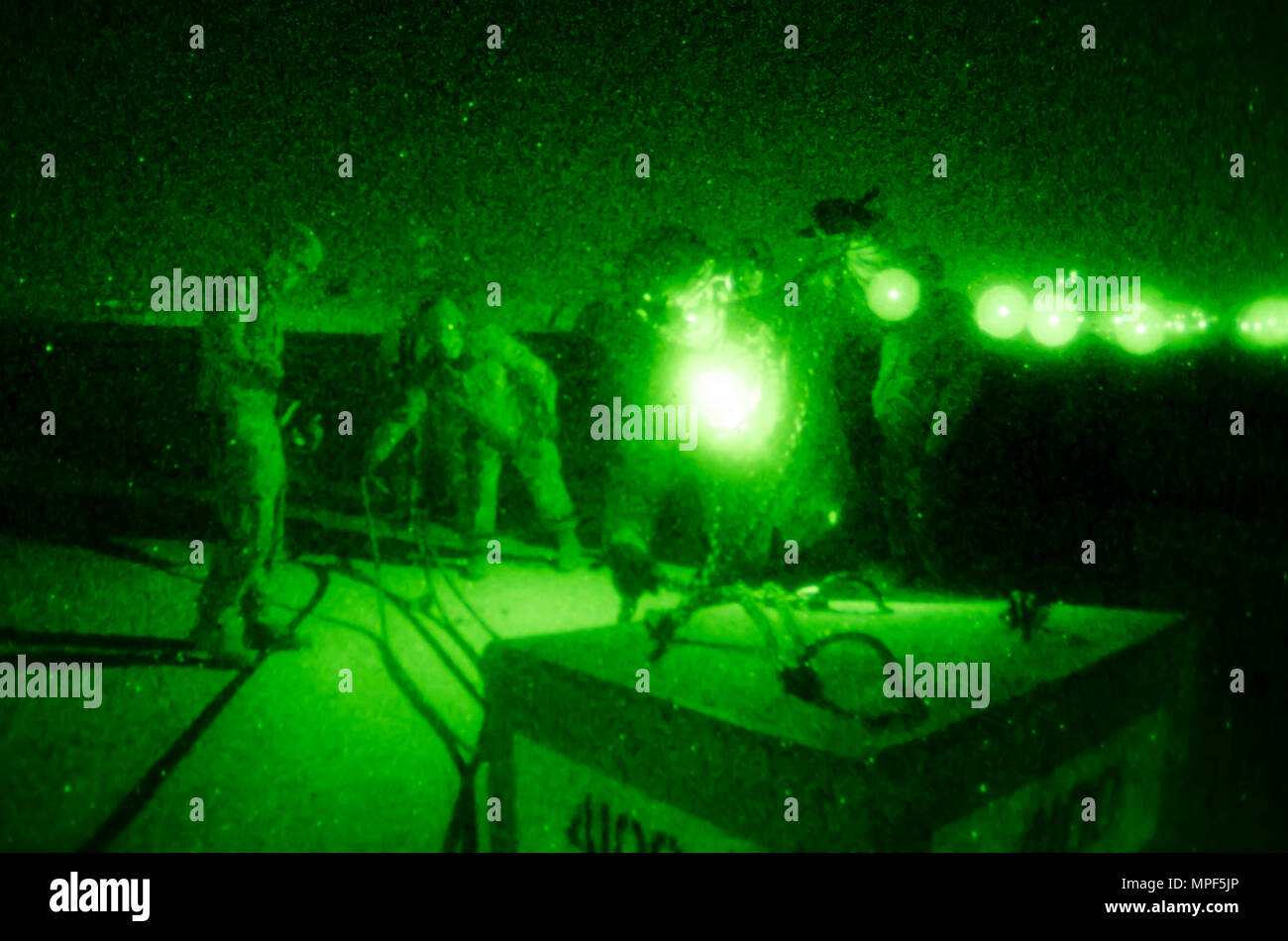 Les soldats de l'armée américaine et portugais affectés au groupement tactique multinational est mènent des opérations de nuit de chargement d'élingue au camp Bondsteel, Kosovo, le 16 février. Les soldats utilisent des lunettes de vision nocturne pour attacher des blocs de béton à un Black Hawk UH-60 stationnaire, piloté par des aviateurs de l'armée américaine. La formation simule la livraison de fournitures et de véhicules aux positions avancées, appuyant les missions de la KFOR et assurant la sûreté et la sécurité des opérations. Le Black Hawk est propulsé par deux turbomoteurs General Electric T700-GE-701C, capables de soulever des cargaisons et du personnel pendant les opérations nocturnes. Banque D'Images