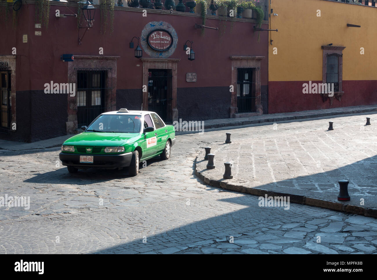 Un taxi vert venant autour du coin d'une rue pavée, dans le centre de San Miguel de Allende, Mexique Banque D'Images