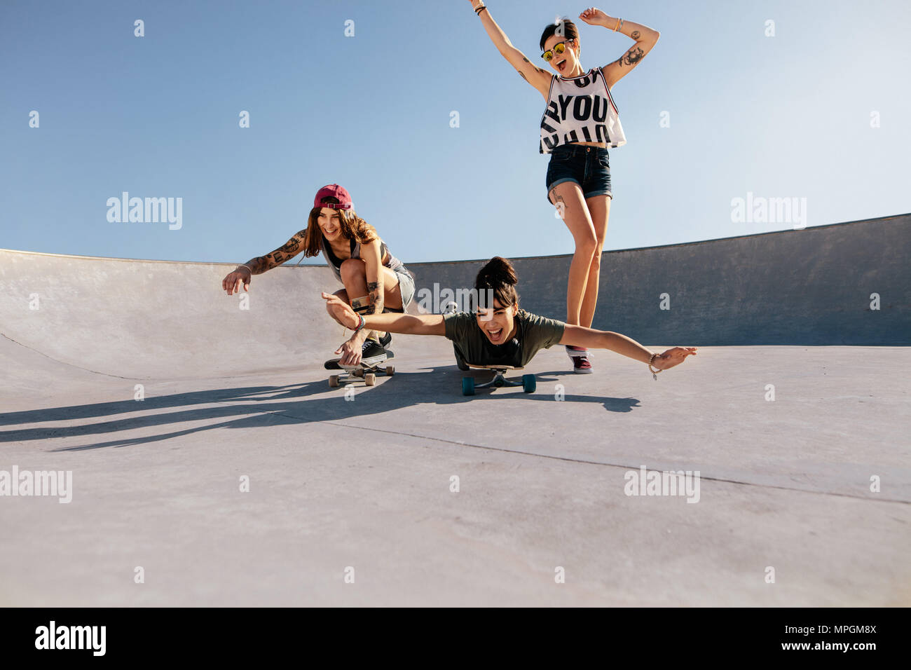 Groupe de femmes jouant avec des planches à roulettes à l'extérieur. Female friends enjoying skateboarding au skate park. Banque D'Images