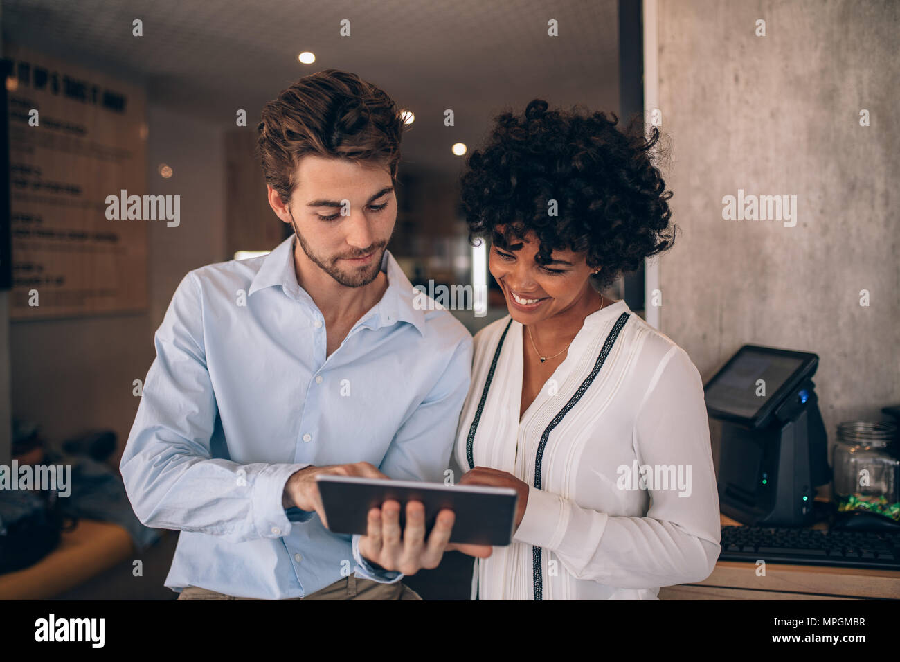 Deux partenaires d'affaires restaurant Standing together and looking at digital tablet. Man and Woman using digital tablet in a cafe. Banque D'Images