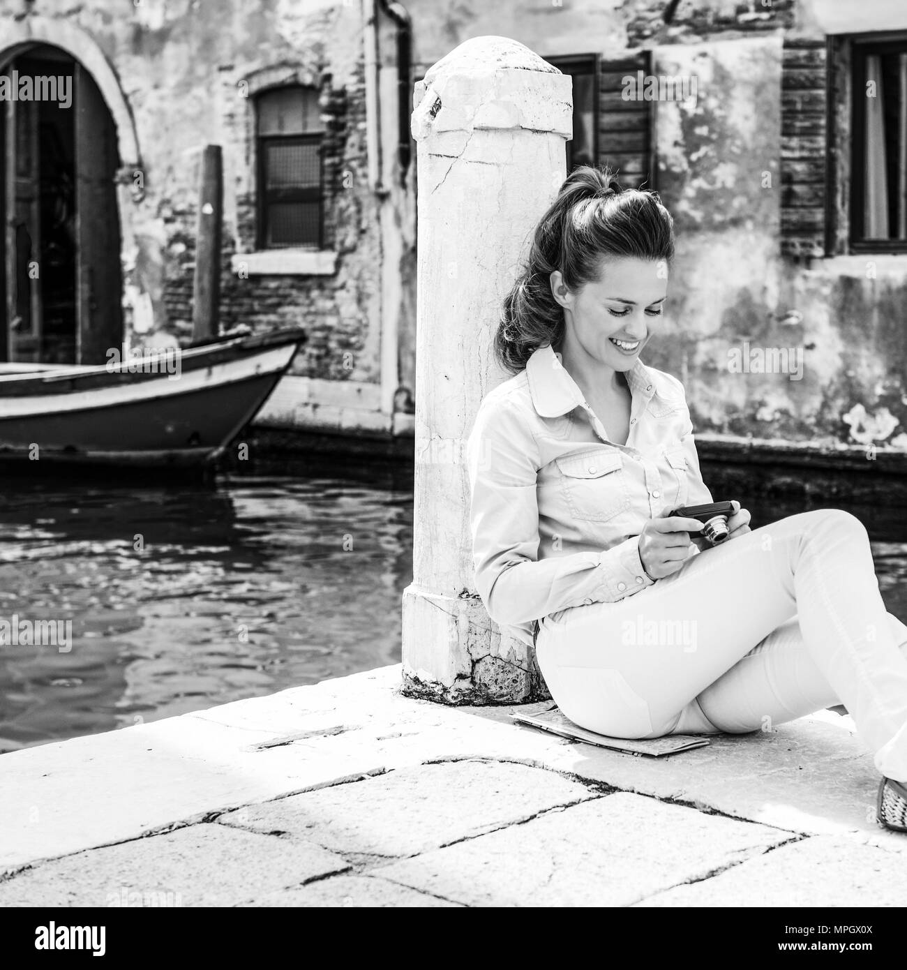 Smiling young woman sitting on street et contrôler in caméra dans Venise, Italie Banque D'Images