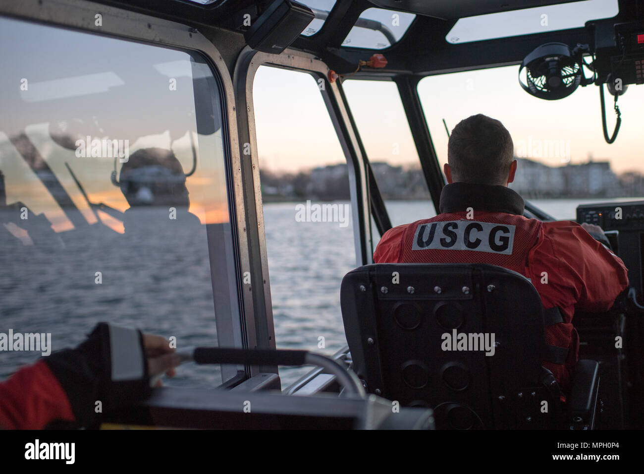 Le compagnon d’un bateau de la Garde côtière américaine pilote un bateau Response de 29 pieds-petit au cours d’une patrouille nocturne sur la rivière Manasquan, New Jersey. Le navire est utilisé pour les opérations de recherche et sauvetage, d'application de la loi et de sécurité maritime. Les membres d'équipage effectuent des tâches de navigation, de manutention des navires et de connaissance de la situation pendant les patrouilles de routine afin de maintenir l'état de préparation opérationnelle et la sécurité publique dans les voies navigables intérieures et côtières. Banque D'Images