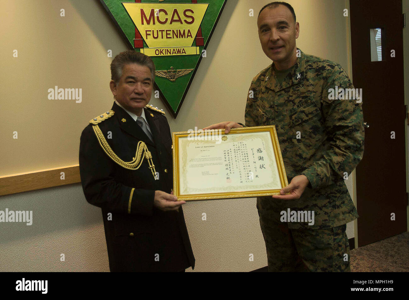 Le chef de la Police de Ginowan Motoki Haneji, gauche, prix Colonel Peter N. Lee avec une lettre d'autorisation 28 février sur Futenma Marine Corps Air Station, Okinawa, Japon. Lee a été reconnu par l'importante pour Haneji le soutien mutuel et la coopération entre MCAS Futenma et le Service de Police de la ville de Ginowan pendant la durée de la commande du chef. Haneji prend sa retraite de ses fonctions de chef de la Police de Ginowan. 'Puisque le chef est arrivée à Ginowan, nous avons eu une très bonne relation avec lui, et à cause de lui, nous avons vraiment renforcé le partenariat entre la gare et la ville," dit Lee, le Banque D'Images