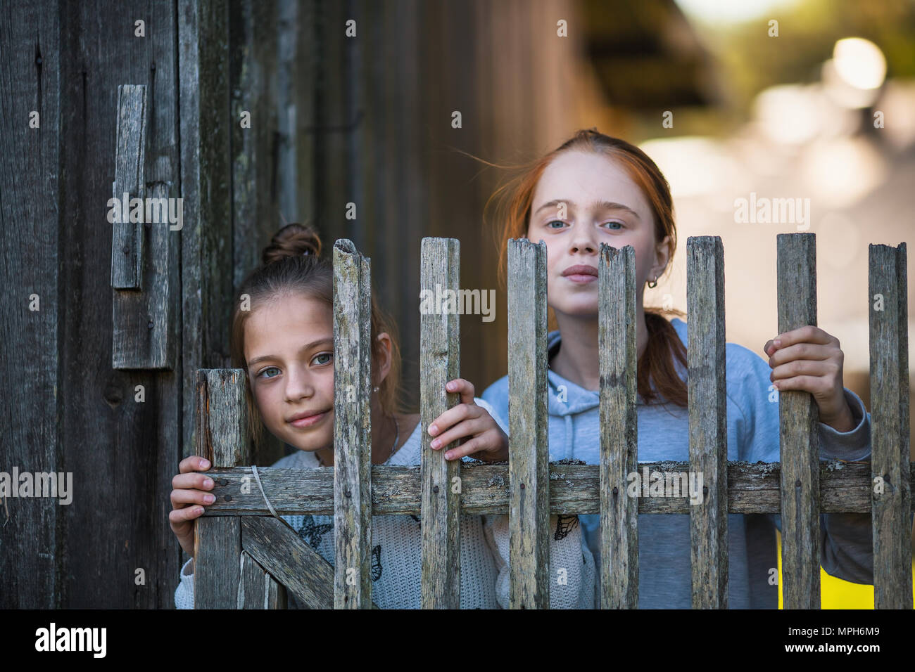 Deux soeurs filles semblent de derrière un village en bois clôture. Banque D'Images