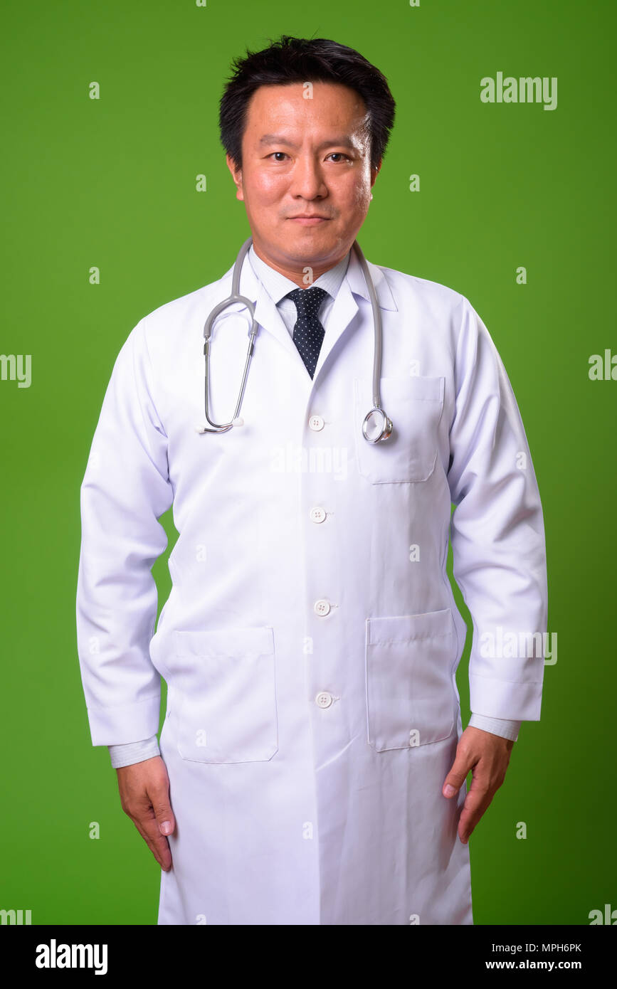 L'homme japonais matures médecin contre un arrière-plan vert Banque D'Images