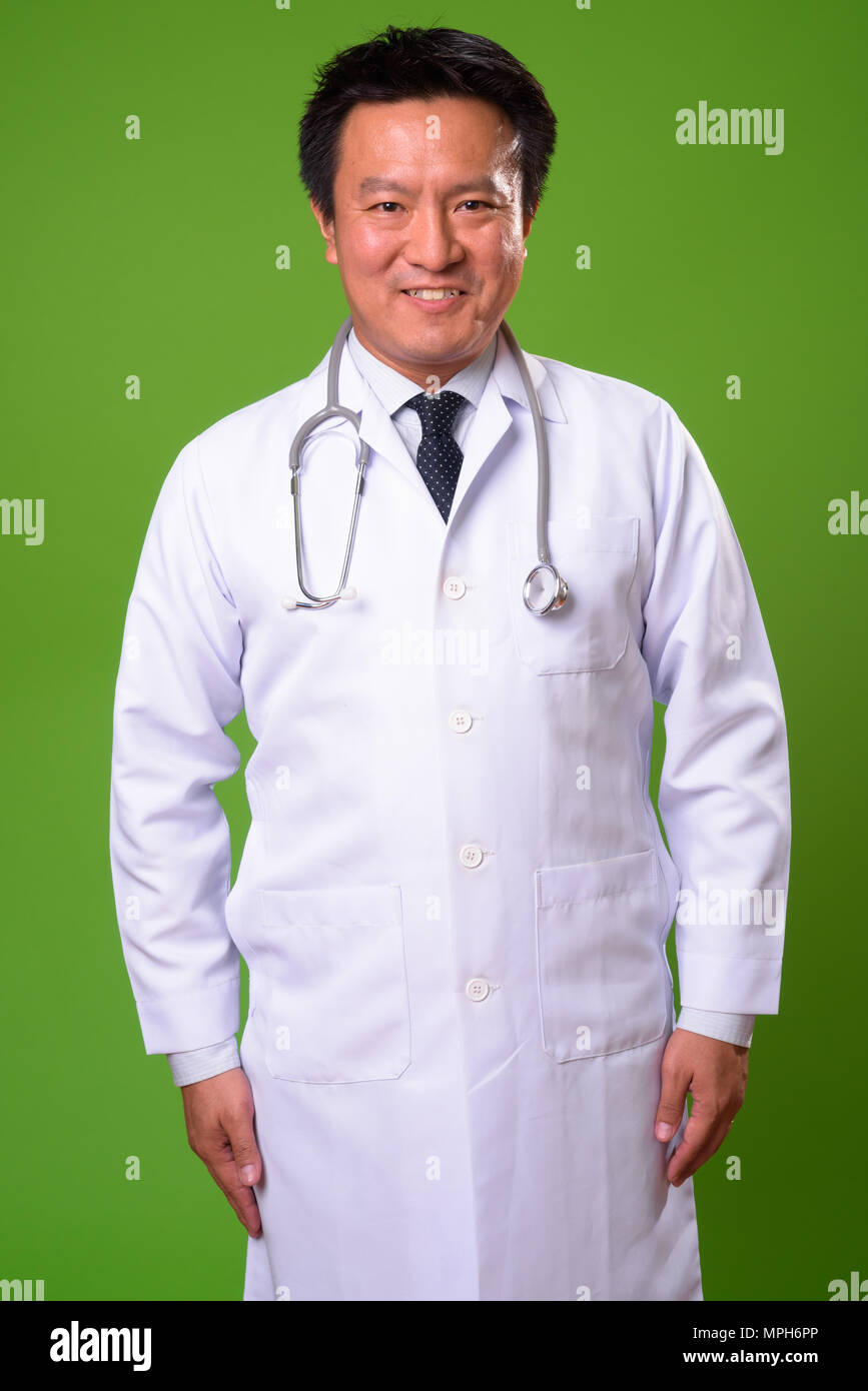 L'homme japonais matures médecin contre un arrière-plan vert Banque D'Images