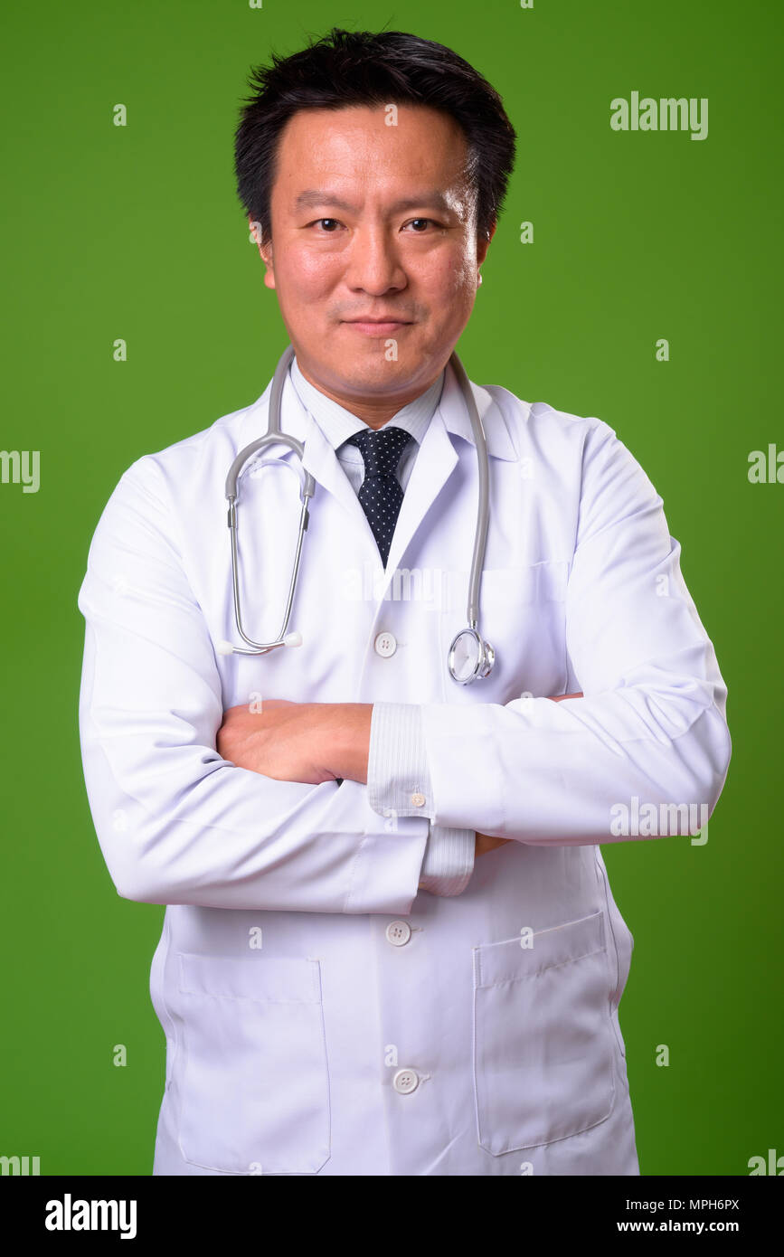 L'homme japonais matures médecin contre un arrière-plan vert Banque D'Images