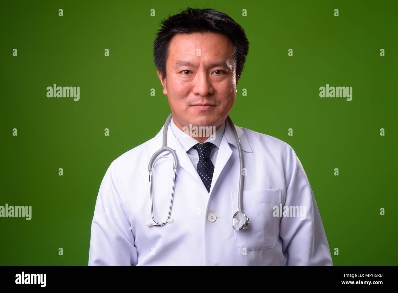 L'homme japonais matures médecin contre un arrière-plan vert Banque D'Images