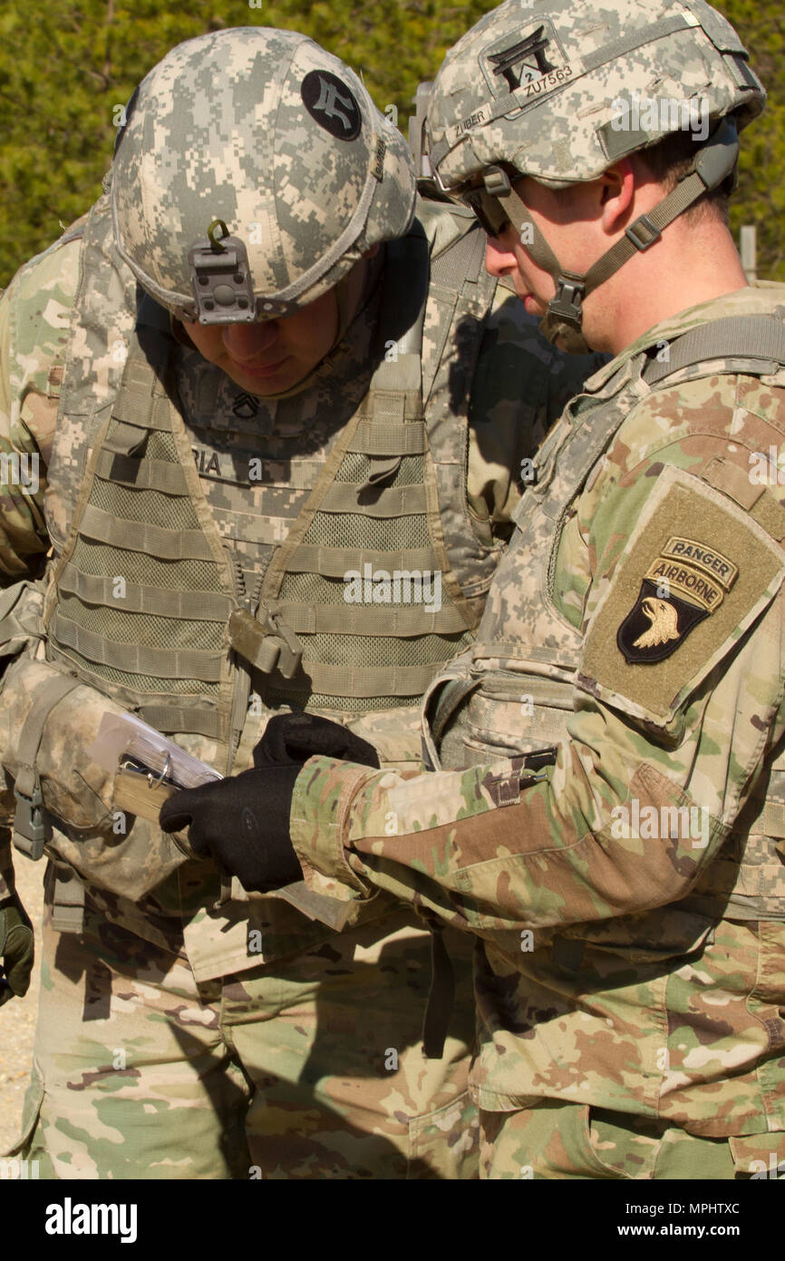 Les soldats de l'Armée américaine affecté à la 101st Airborne Division (Air Assault), regardez la carte données avant d'utiliser un télémètre désignateur laser léger 2H pour fournir un appui-feu acquisition d'objectifs et de reconnaissance au cours de l'appui aérien rapproché avec la formation des pilotes aux commandes d'un AH-1W Super Cobra hélicoptère de combat et d'un hélicoptère UH-1Y Venom au cours de l'exercice guerrier 78-17-01 le 17 mars, 2017 at Joint Base McGuire-Dix-Lakehurst. Contrôles d'incendie affectés au siège de spécialiste et le Siège Batterie, 3e Bataillon, 320e Régiment d'artillerie, avec la direction de la Société A (Easy Com Banque D'Images