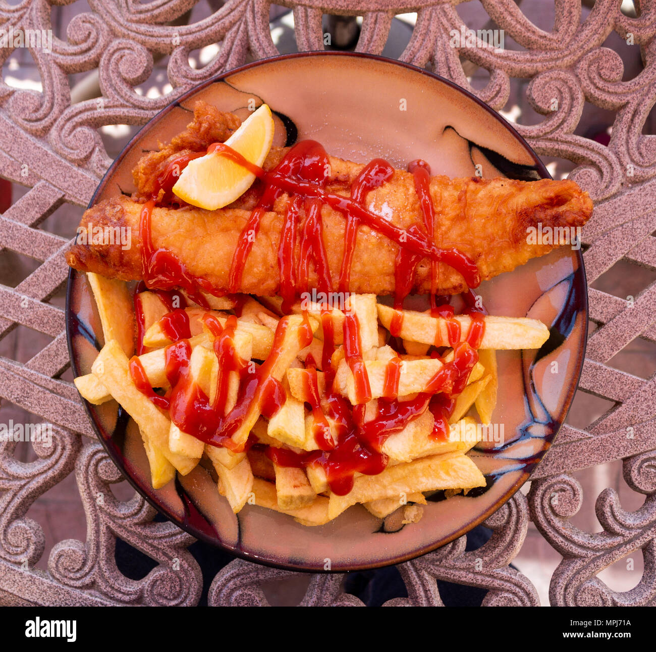 Repas de poisson et frites avec un quartier de citron ou de citron sur filtre en coin d'une table. Banque D'Images