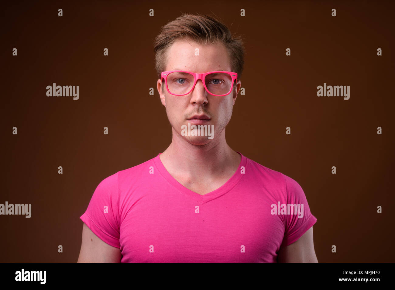 Beau jeune homme portant des lunettes et chemise rose contre bro Banque D'Images