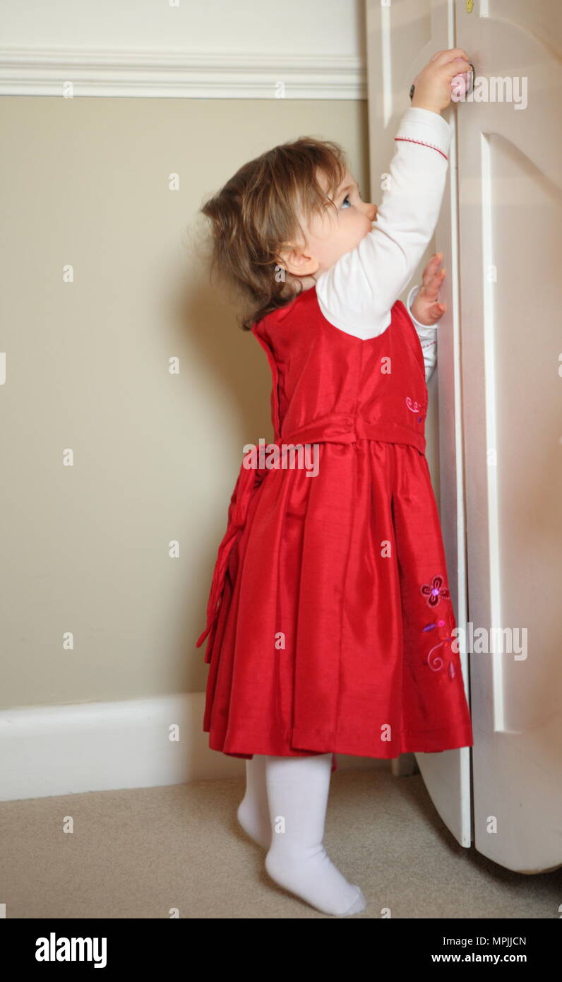 Bébé curieux bébé fille en robe en soie rouge ouvre une armoire de  rangement, l'âge de 18 ans à 24 mois Mars 2010 --- Image par © Paul  Cunningham Photo Stock - Alamy