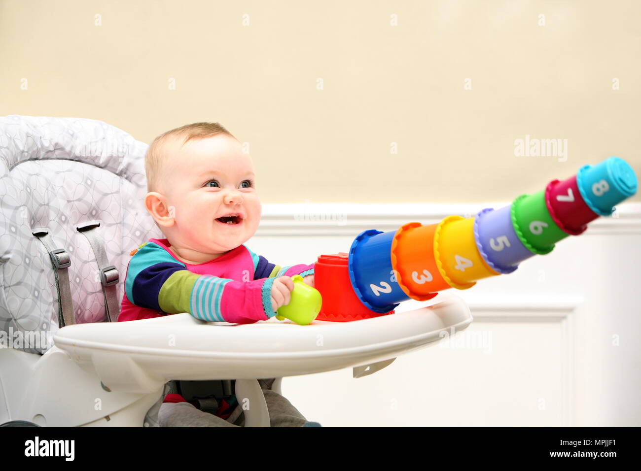 Chaise haute bébé en riant comme la numérotation des blocs empilés et basculer, l'âge de 6 à 9 mois, avril 2009 --- Image par © Paul Cunningham Banque D'Images