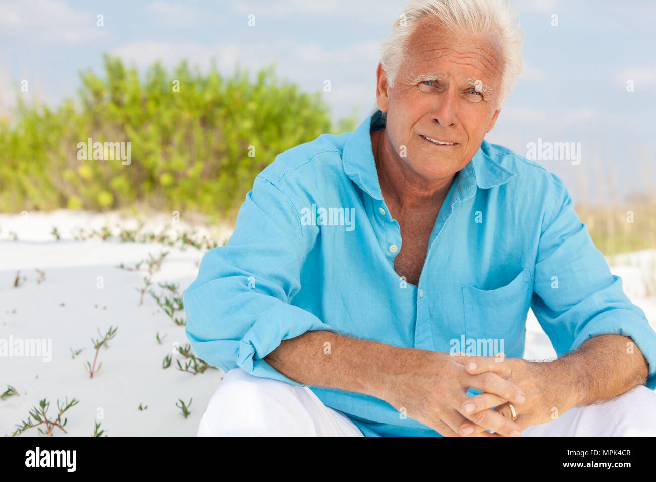 Portrait of a handsome attrayant réfléchis inquiets concerné senior man s'asseoir à l'extérieur, sur une plage et smiling Banque D'Images