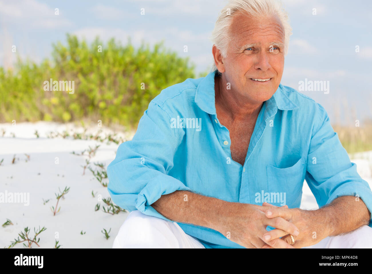 Portrait of a happy attractive thoughtful handsome man s'asseoir à l'extérieur, sur une plage et smiling Banque D'Images