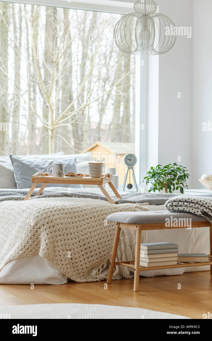 L'intérieur de chambre à coucher avec un lit king-size avec des oreillers et une couverture grise, grande fenêtre et plancher en bois Banque D'Images