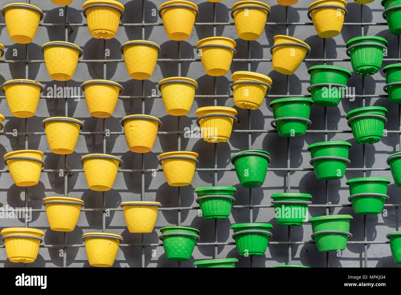 L'art de mur de décor avec grille couleur vert vif et jaune des pots de fleurs sur mur de béton. Ville moderne, la texture d'arrière-plan Banque D'Images