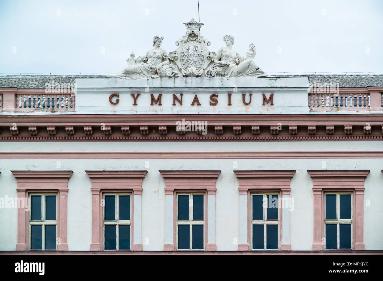 Haut de savoirs traditionnels, rose, ornate building montrant titre 'gymnasium' (qui signifie école) ainsi que des statues sculptées pour l'éducation et des armoiries en Tchèquia Banque D'Images