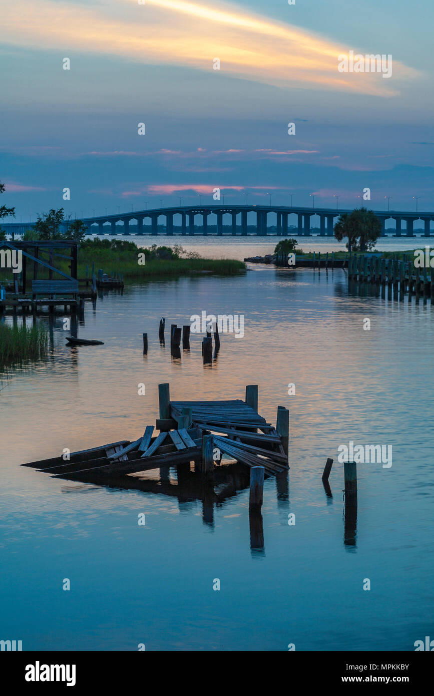 Pont de la baie de Saint-Louis derrière les vestiges d'un ancien quai en bois dans un canal à Henderson point à col Christian, Mississippi au coucher du soleil Banque D'Images