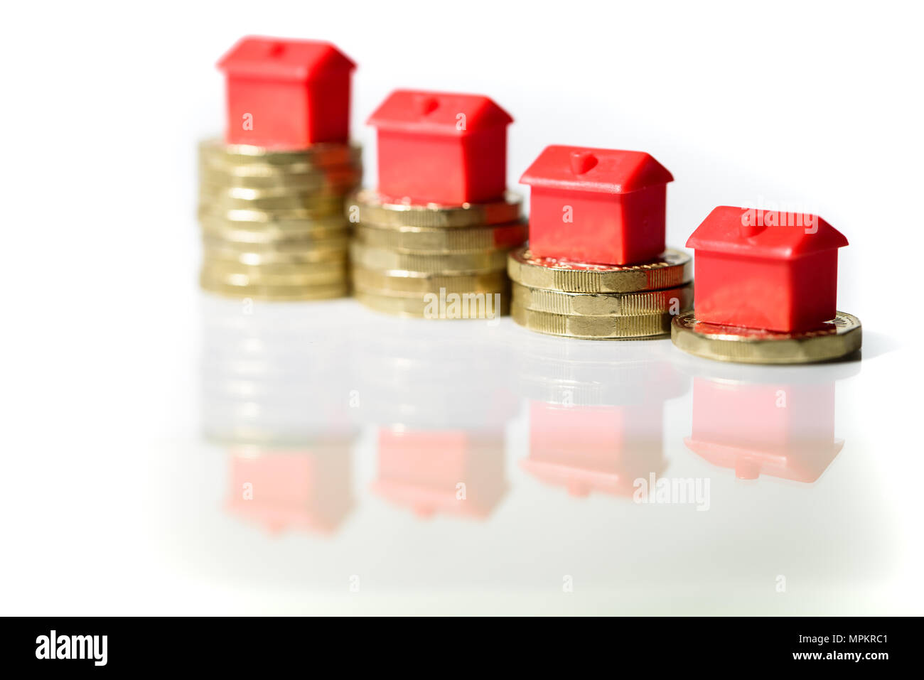 Maisons miniature reposant sur de nouvelles piles de monnaie livre concept pour la propriété, d'hypothèques et de l'investissement immobilier Banque D'Images