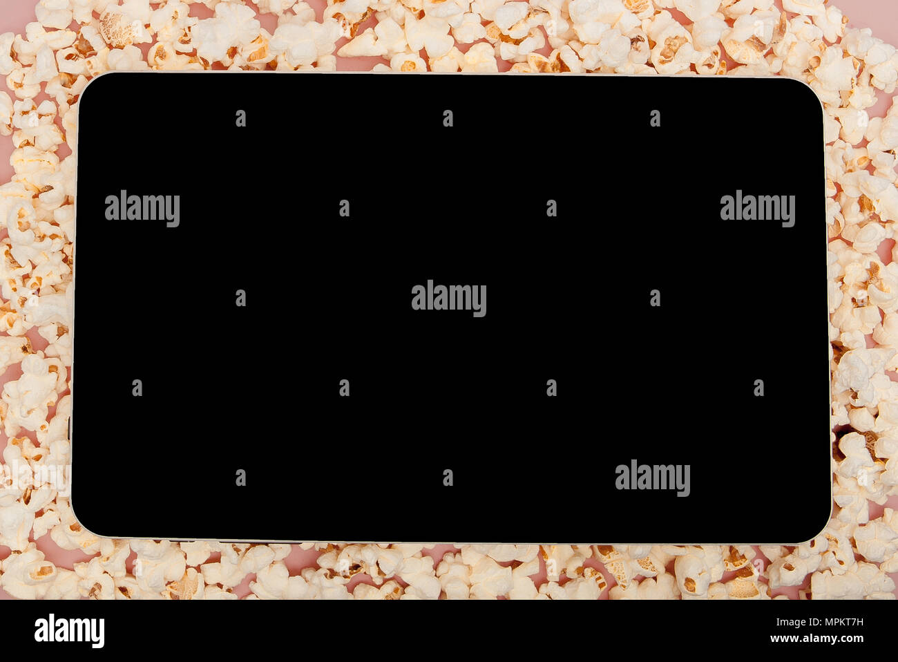 Popcorn with digital tablet sur fond rose. Banque D'Images