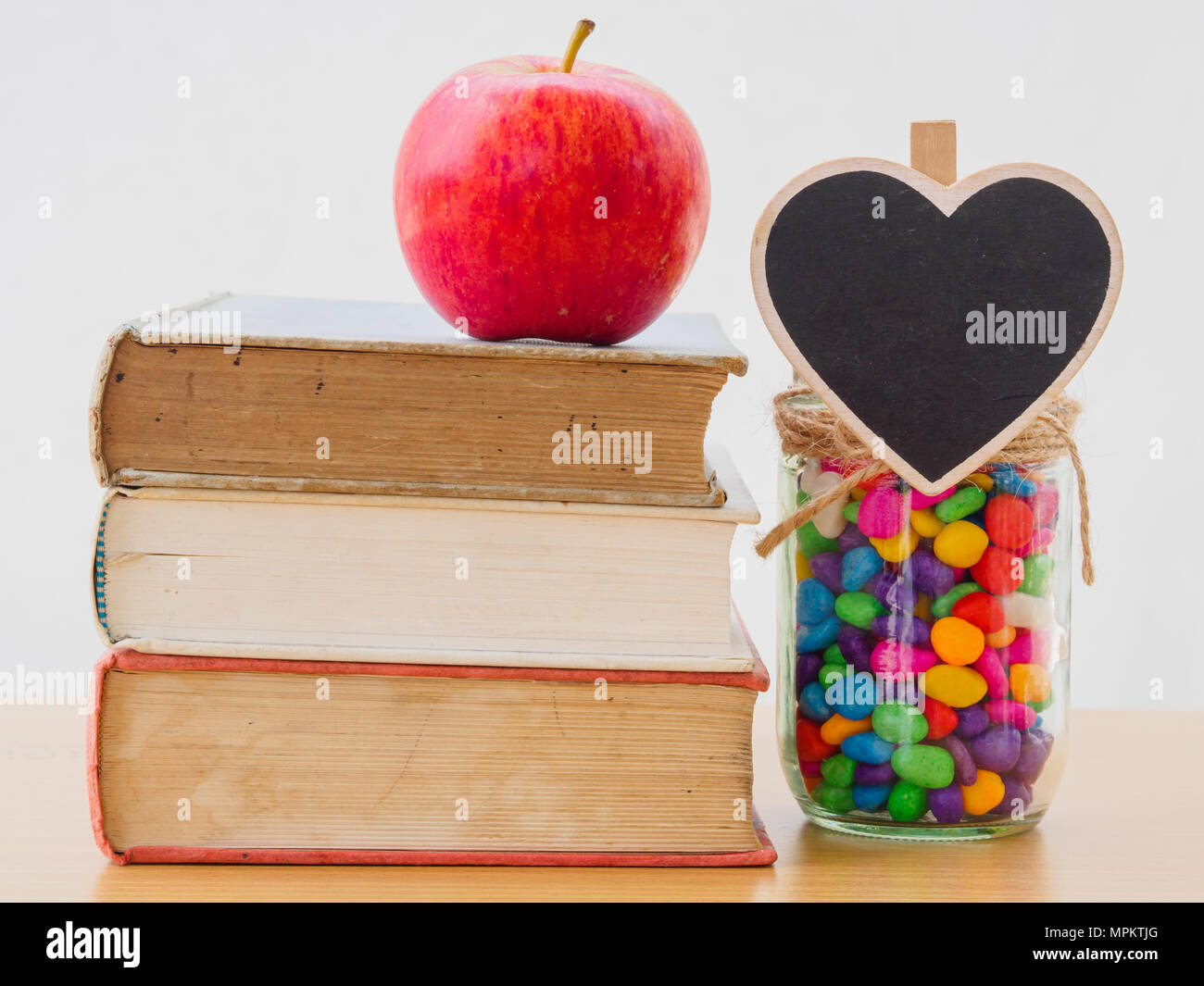 Concept de la Journée mondiale du livre. Pomme Rouge mis sur de vieux livres avec coeur noir et coloré de stons in jar Banque D'Images