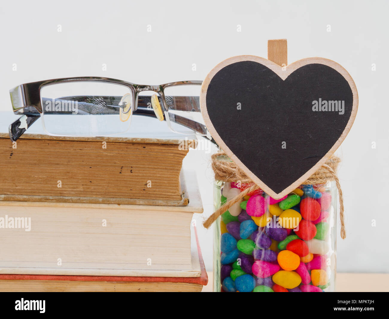 La Journée mondiale du livre concept. Verres mis sur de vieux livres avec coeur noir et coloré de stons in jar Banque D'Images