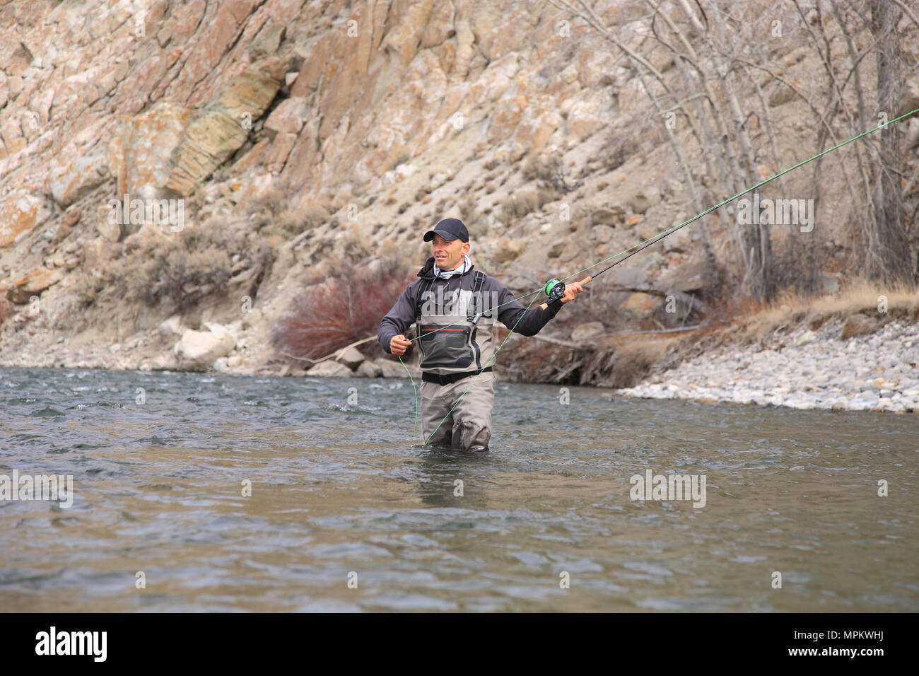 un pêcheur à la mouche adulte se frayant un chemin et se jette dans une rivière Idaho Banque D'Images