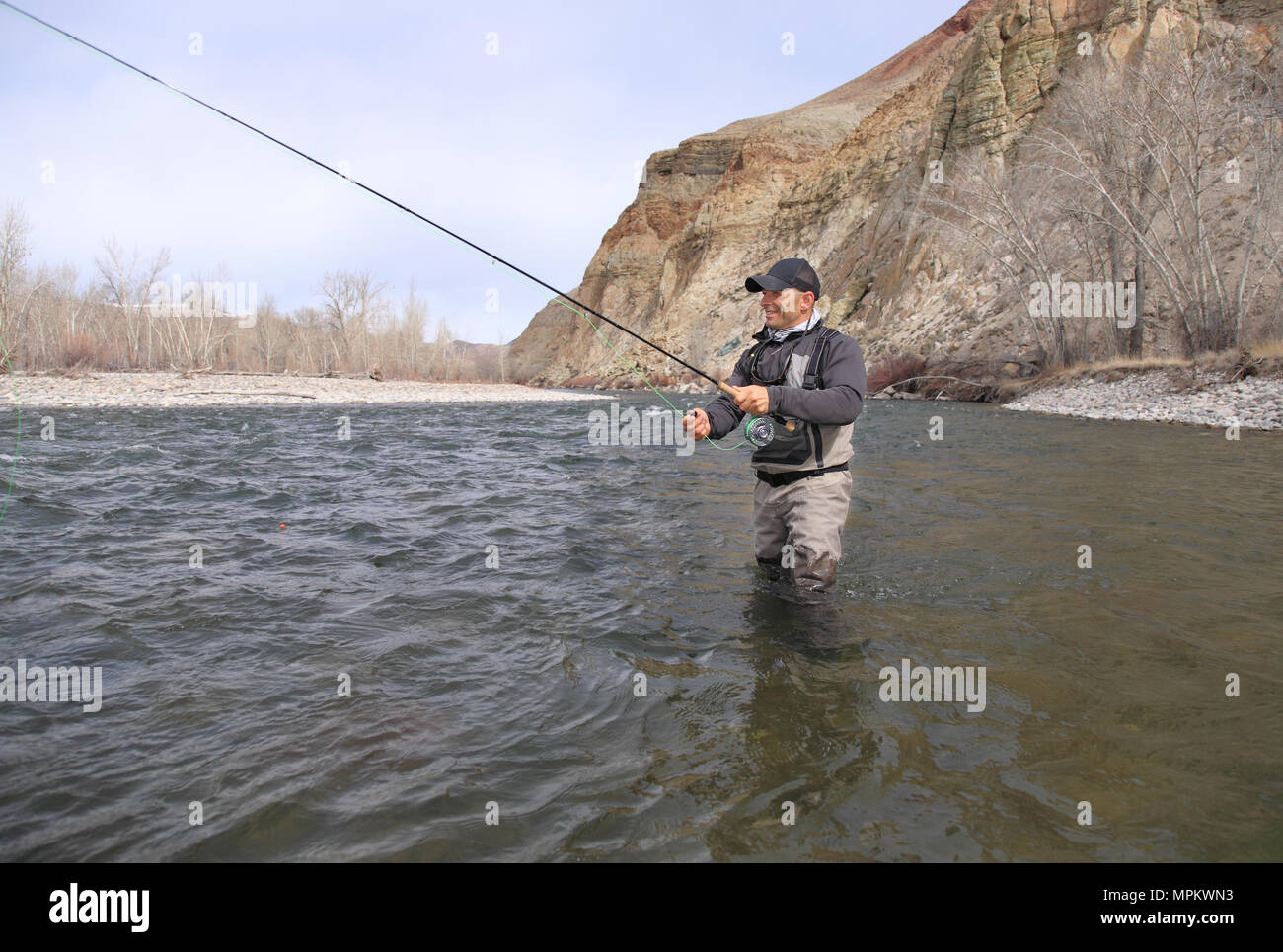 Pêcheur de mouche adultes pataugeant et moulage sur une rivière Banque D'Images