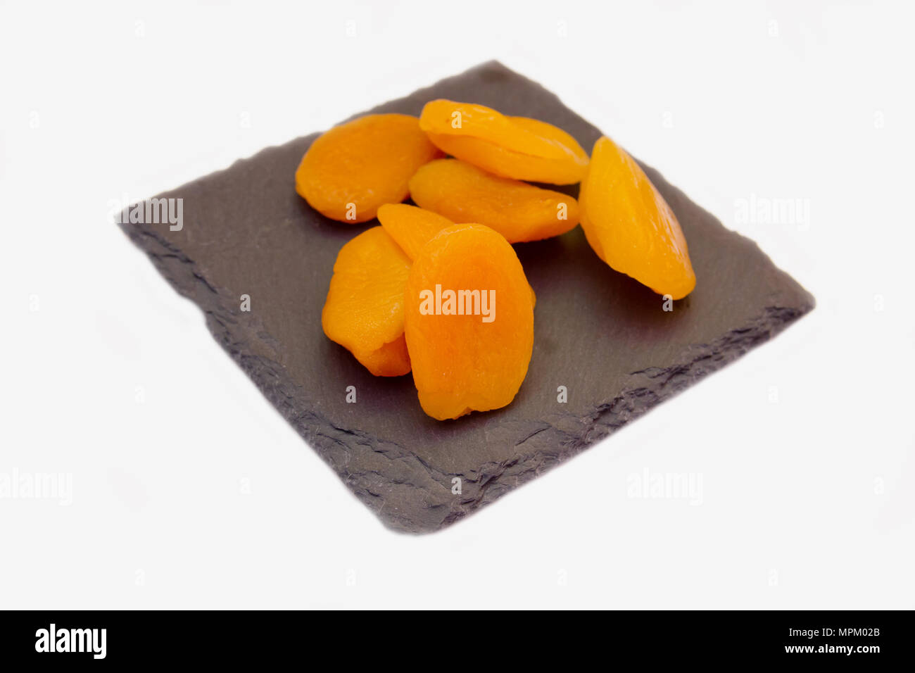 Abricots dénoyautées sur ardoise Plaque sur fond blanc vue rapprochée Banque D'Images
