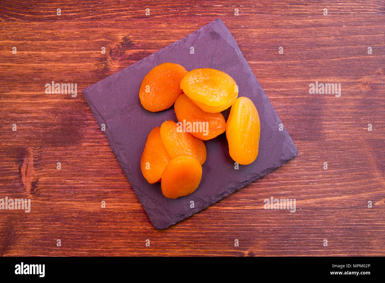 Abricots dénoyautées sur ardoise plateau sur une table en bois vu de dessus Banque D'Images