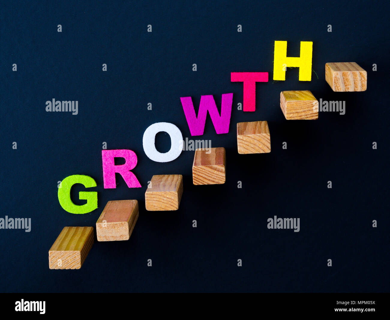 Bloc de bois qu'à l'étape d'empilage d'escaliers avec des couleurs "Croissance" sur parole en fond noir. Concept d'affaires à la réussite du processus. Banque D'Images