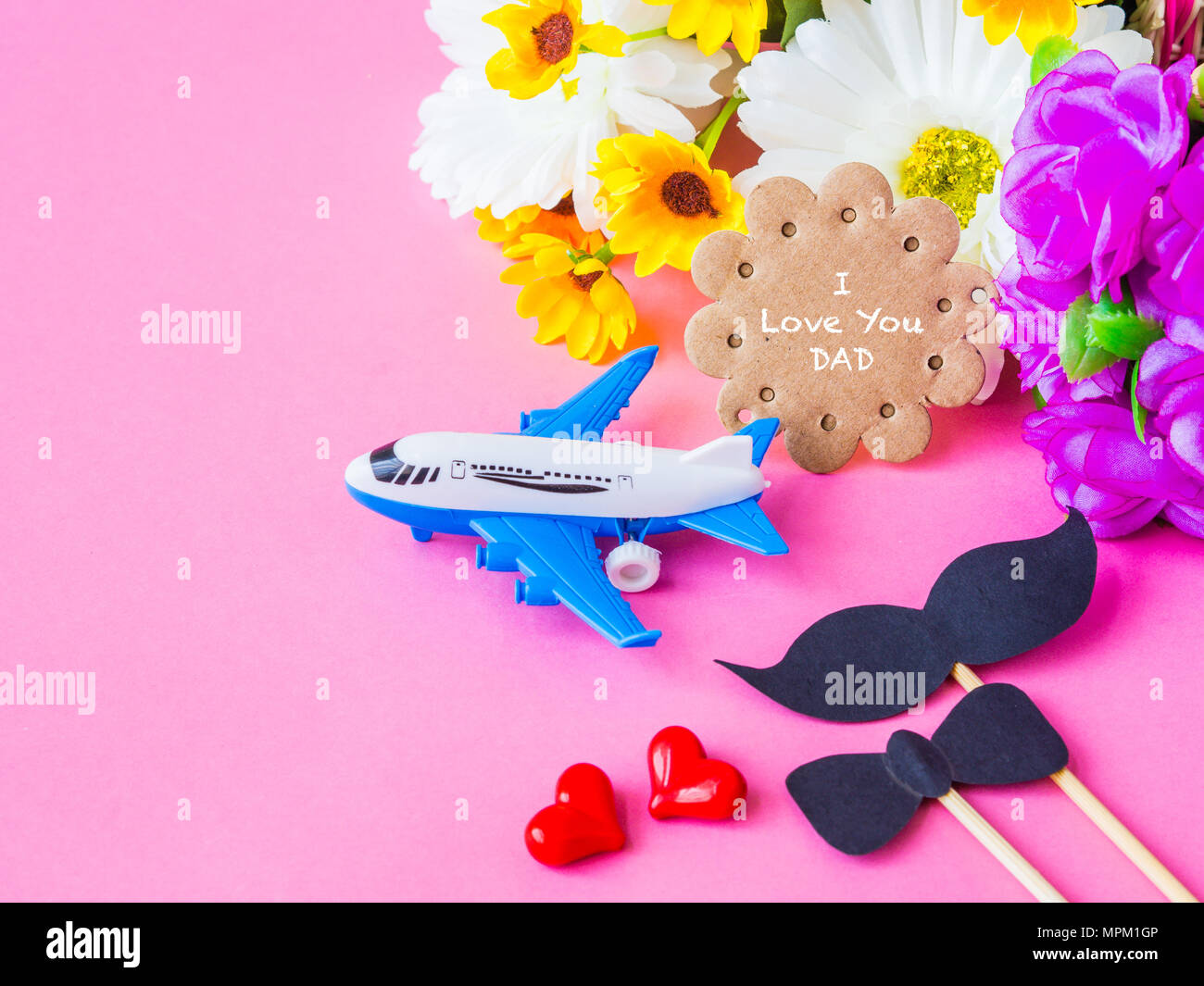 Concept de la fête des pères. Je t'aime papa message avec fleur blanc et jaune, deux cœur rouge, une moustache noire et bairplane modèle sur fond rose Banque D'Images