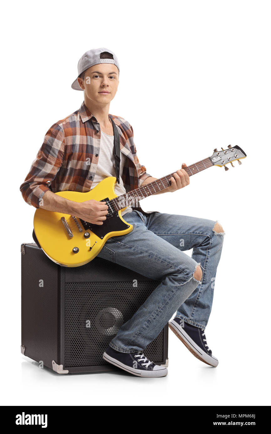 Adolescent avec une guitare électrique assis sur un amplificateur isolé sur fond blanc Banque D'Images