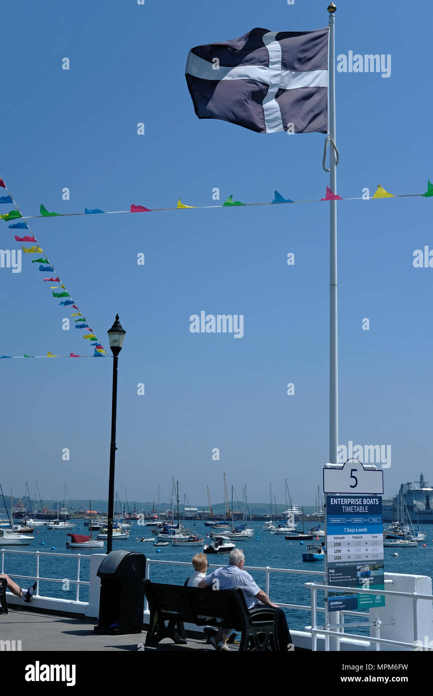 Un couple de retraités s'asseoir au soleil dans la région de Falmouth, Cornwall sous le drapeau cornouaillais. St Piran's. Banque D'Images