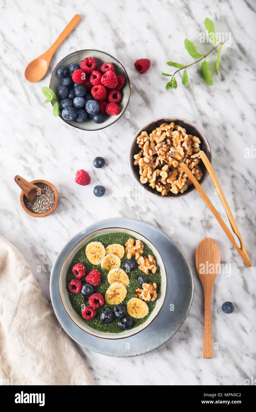 Bol Bouddha vert de chia pudding avec des tranches de banane, bleuets, framboises et noix Banque D'Images