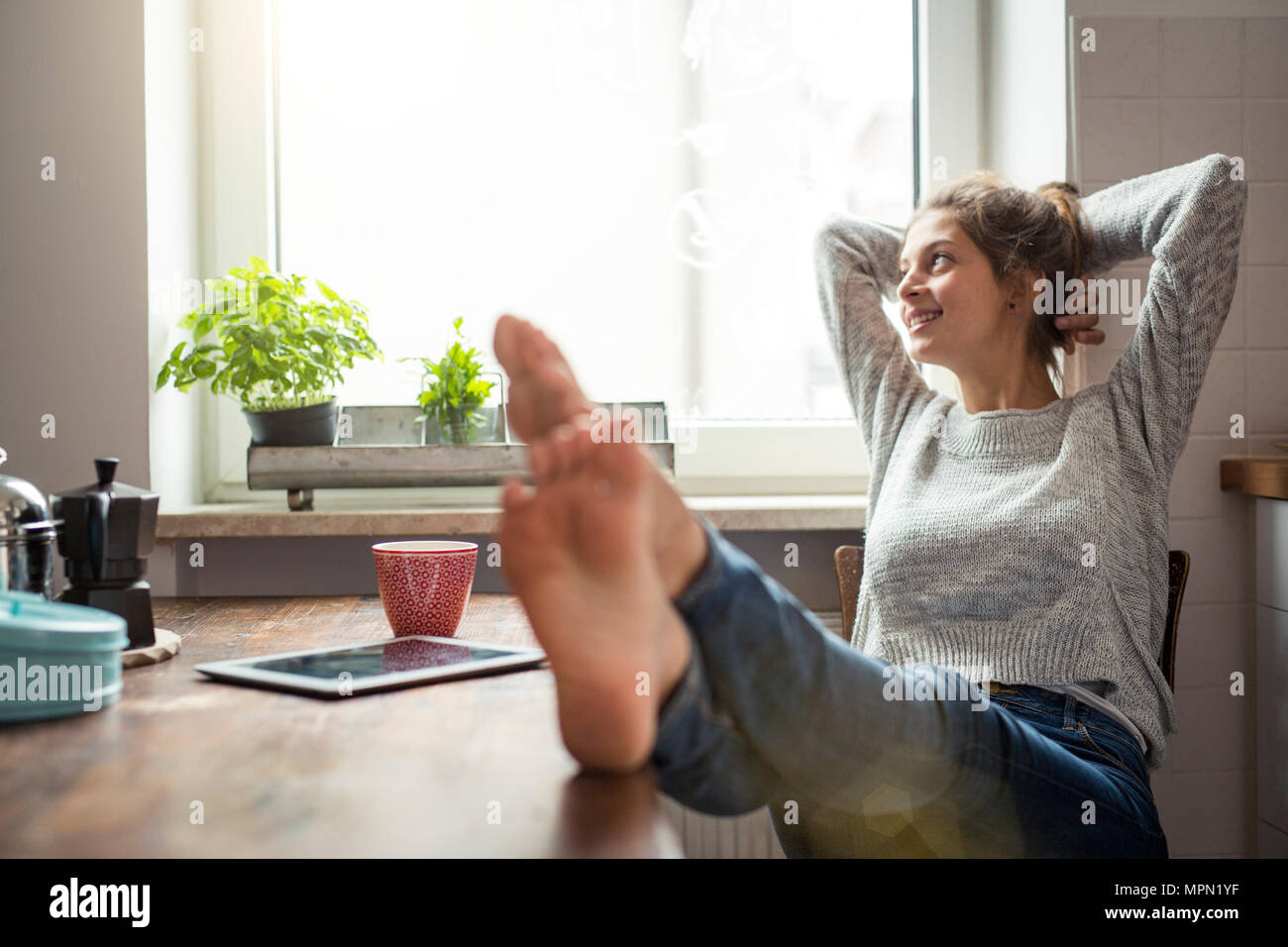 Woman sitting at table in kitchen relaxing Banque D'Images