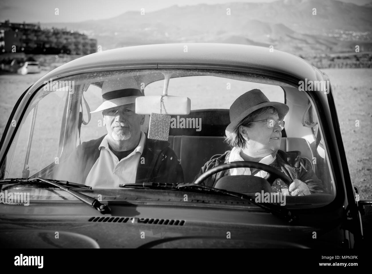 Deux personnes voyageant à l'intérieur et la conduite mature un vieux millésime. voiture rétro noir et blanc image avec deux beaux modèle senior bénéficiant de la vie à la retraite Banque D'Images
