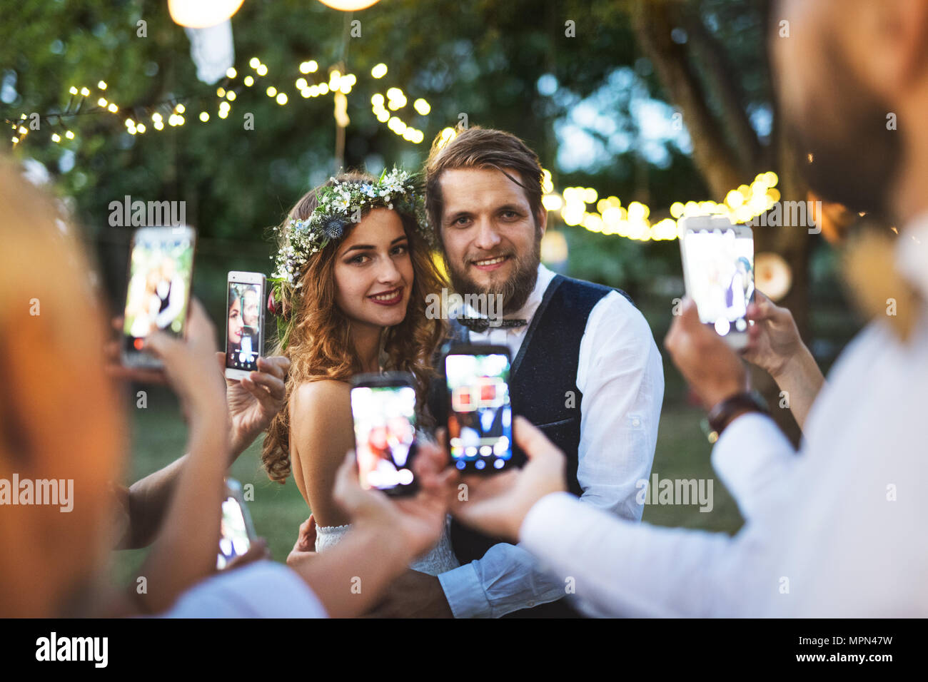 Les clients avec les smartphones de prendre photo de mariés à réception de mariage à l'extérieur. Banque D'Images