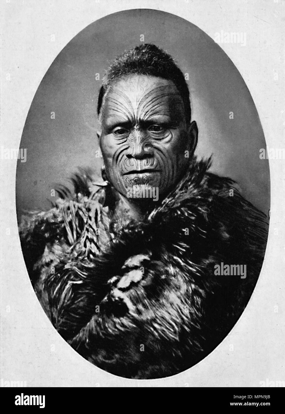 Un chef Maori tatoué et richement avec face météo cape, 1902. Artiste : Josiah Martin. Banque D'Images