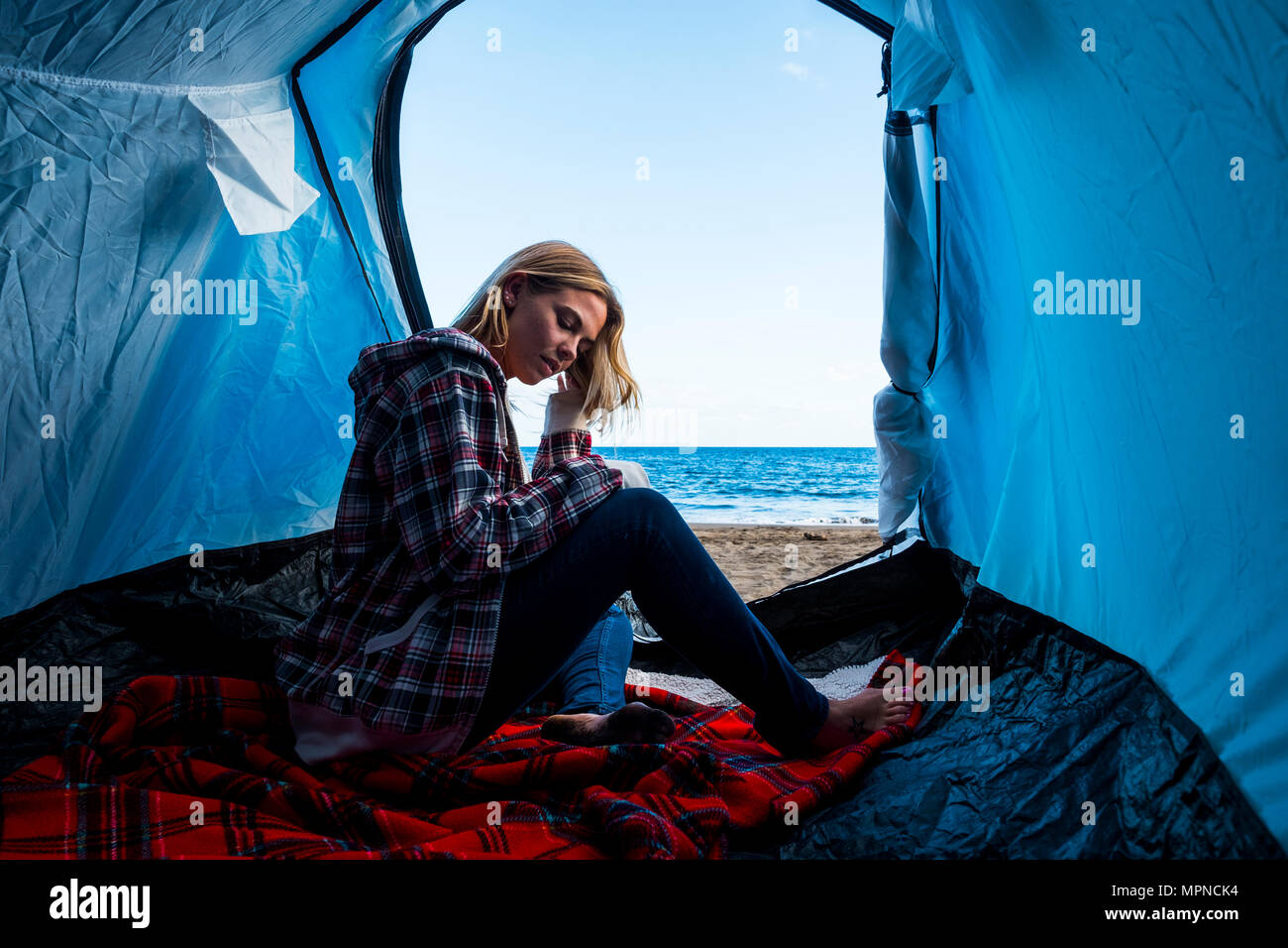 Belle jeune femme blonde caucasienne dans une tente sur la plage près de l'océan vivent une vie pleine de liberté et d'indépendance Banque D'Images