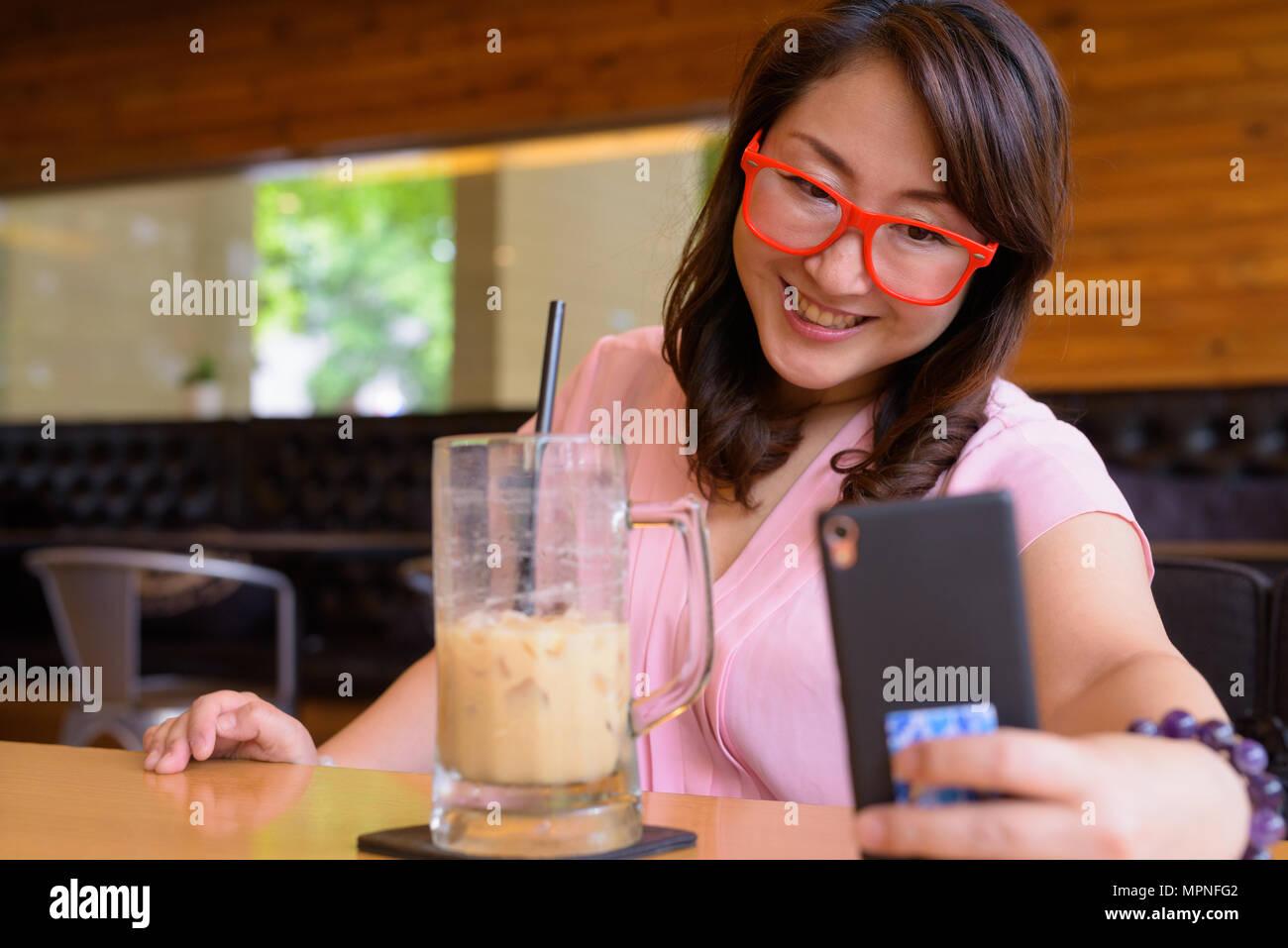 Mature Asian woman relaxing at coffee shop Banque D'Images