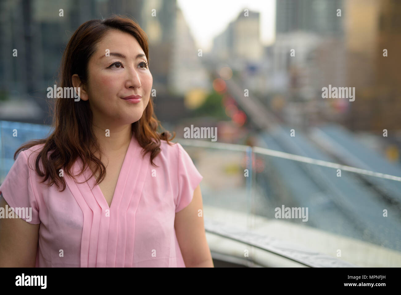 Mature Asian woman contre vue sur la ville Banque D'Images