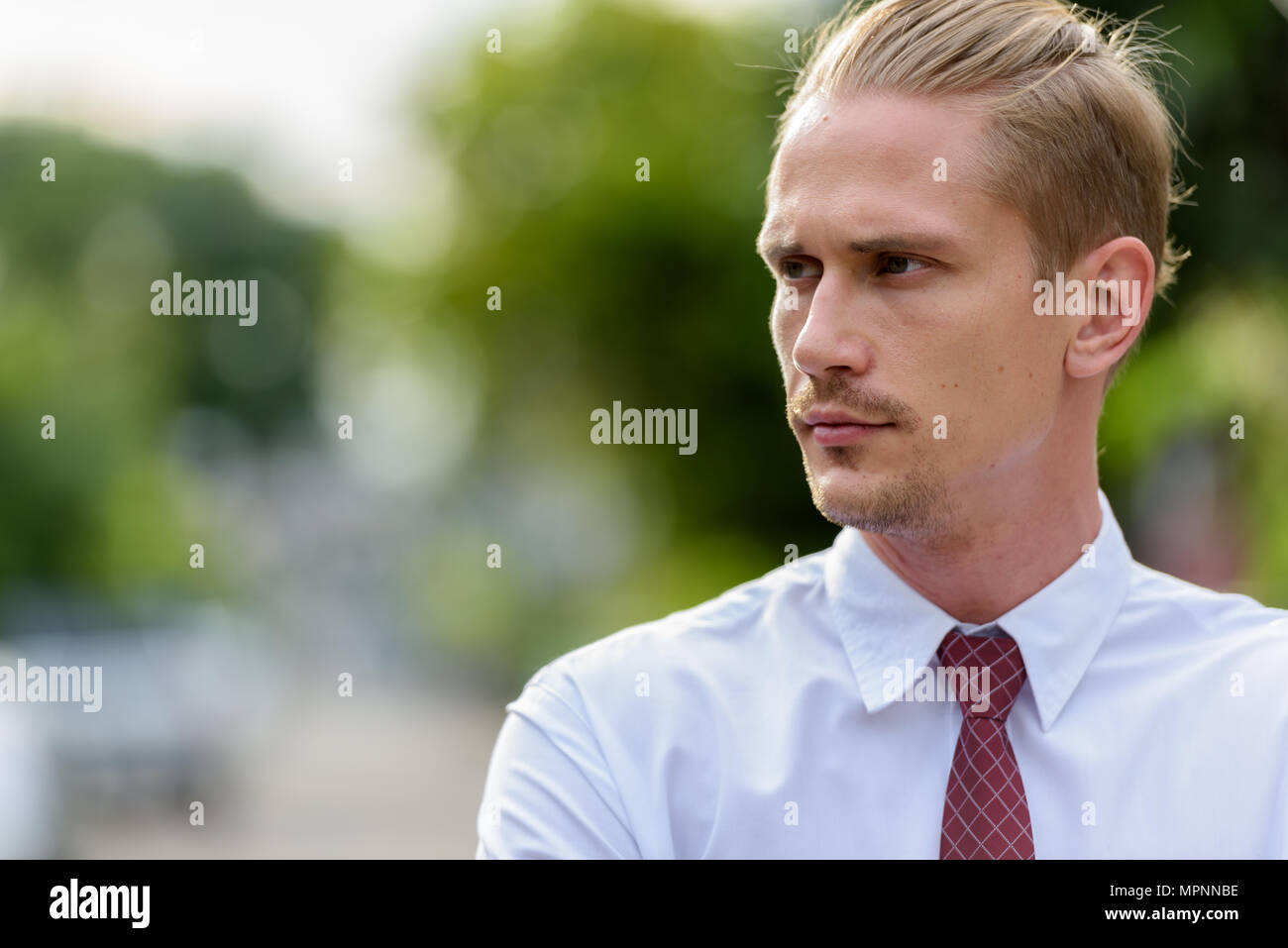 Close up of young handsome businessman thinking while looking at Banque D'Images