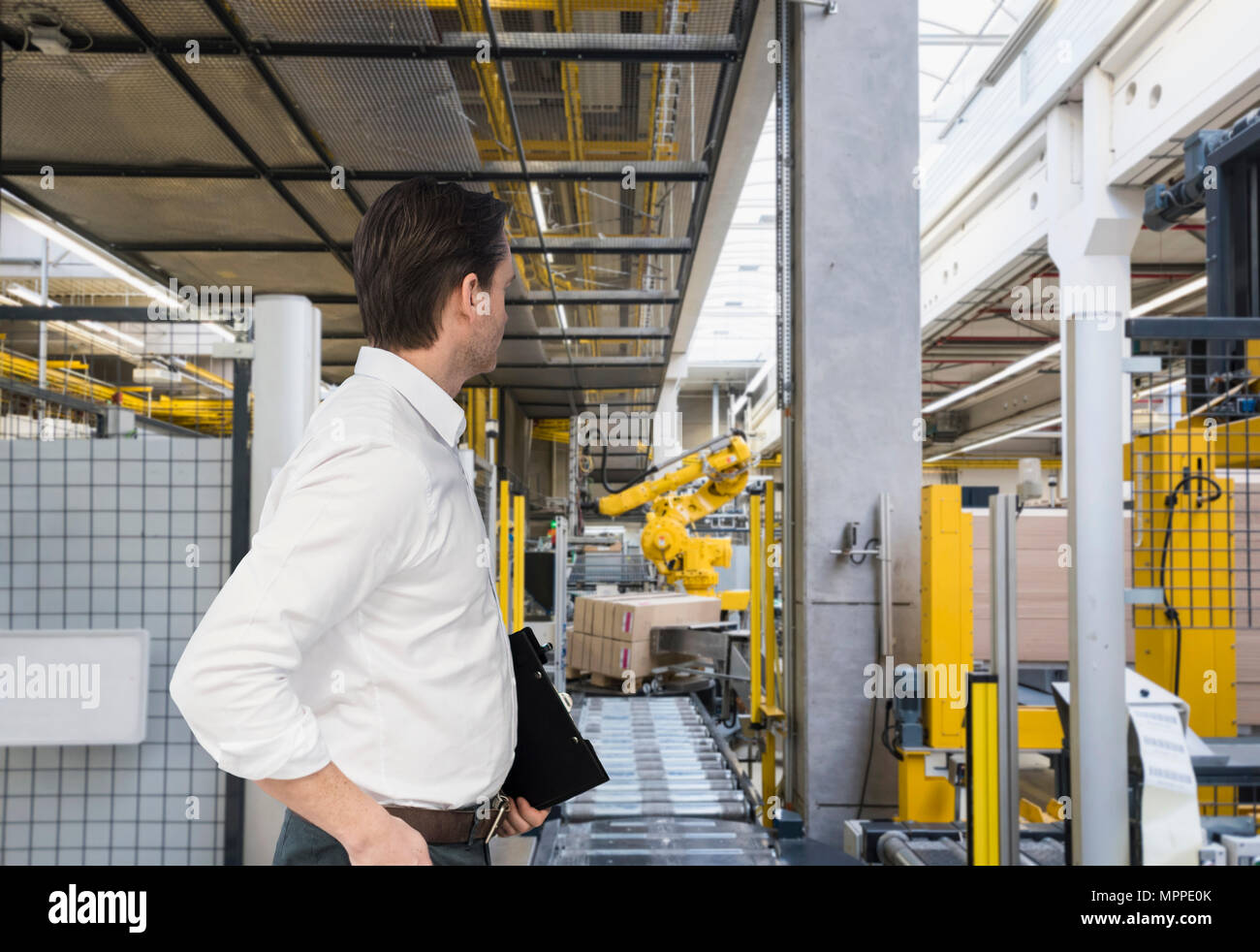 Businessman with clipboard sur magasin d'usine à étage autour de Banque D'Images